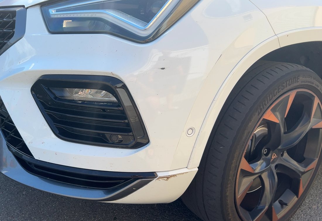 Aufgerissene Frontschürze und abgescheuerte Spoilerlippe eines weißen Cupra Ateca, Schadenhöhe 14.802,25 €